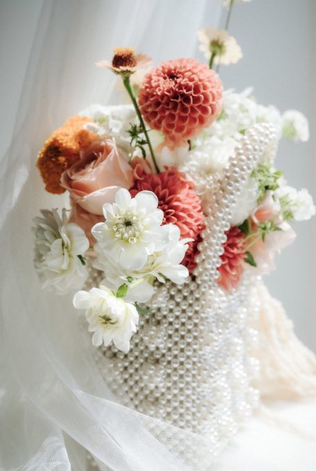 Blush, white and burnt orange bouquet sitting in high fashion pearl laden clutch The Glasshouse Auckaland Wedding Ana Galloway Photography