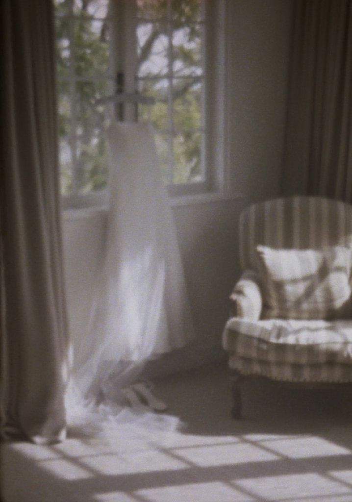 Still frame from a super 8 film footage showing a wedding dress hanging up