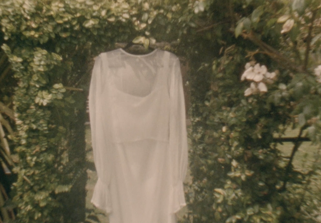 Still frame from a super 8 film footage showing a wedding dress hanging up