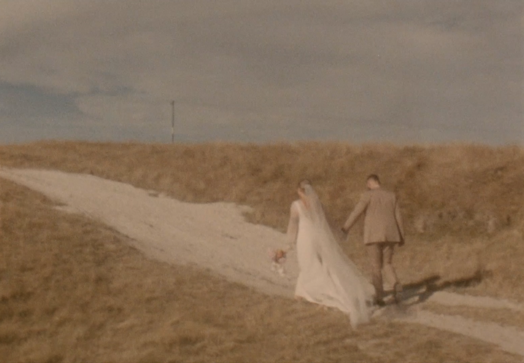 Still frame from a super 8 film footage showing a couple walking together in a field