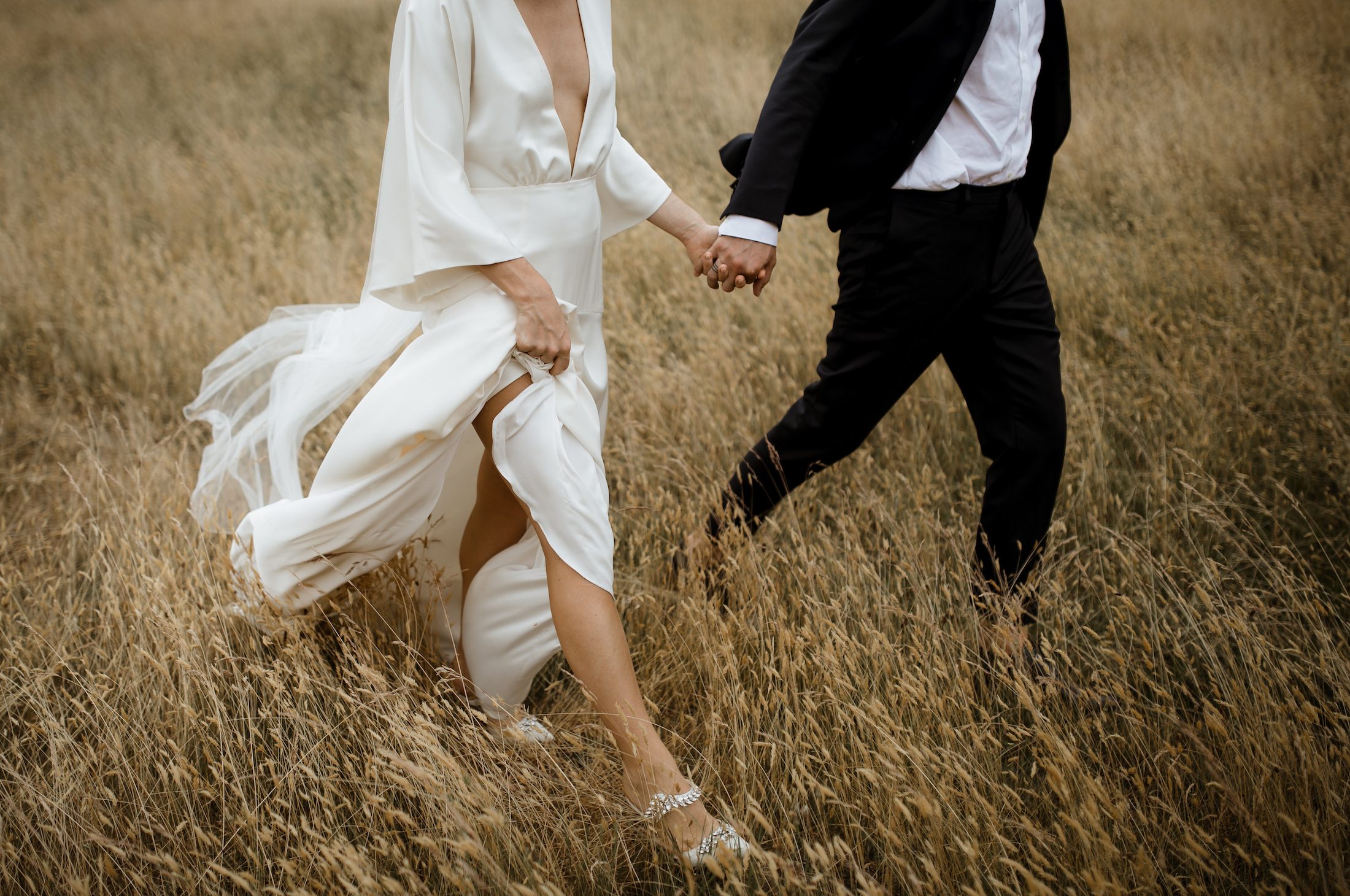 Modern Bride and Groom walking through long summer grass