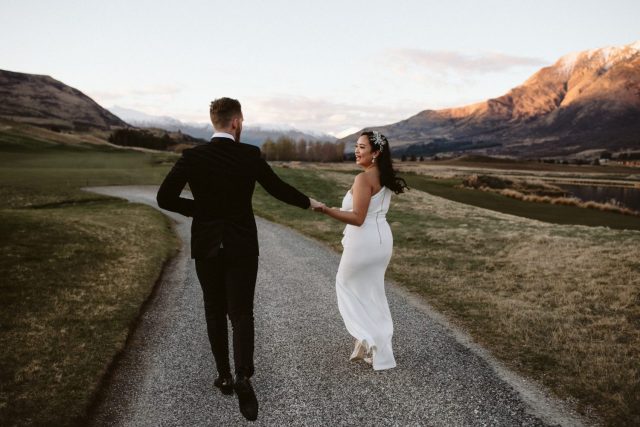 Bride and groom running hand in hand surrounded by the mountains in Queenstown. Jacks Point Wedding Ana Galloway Photography