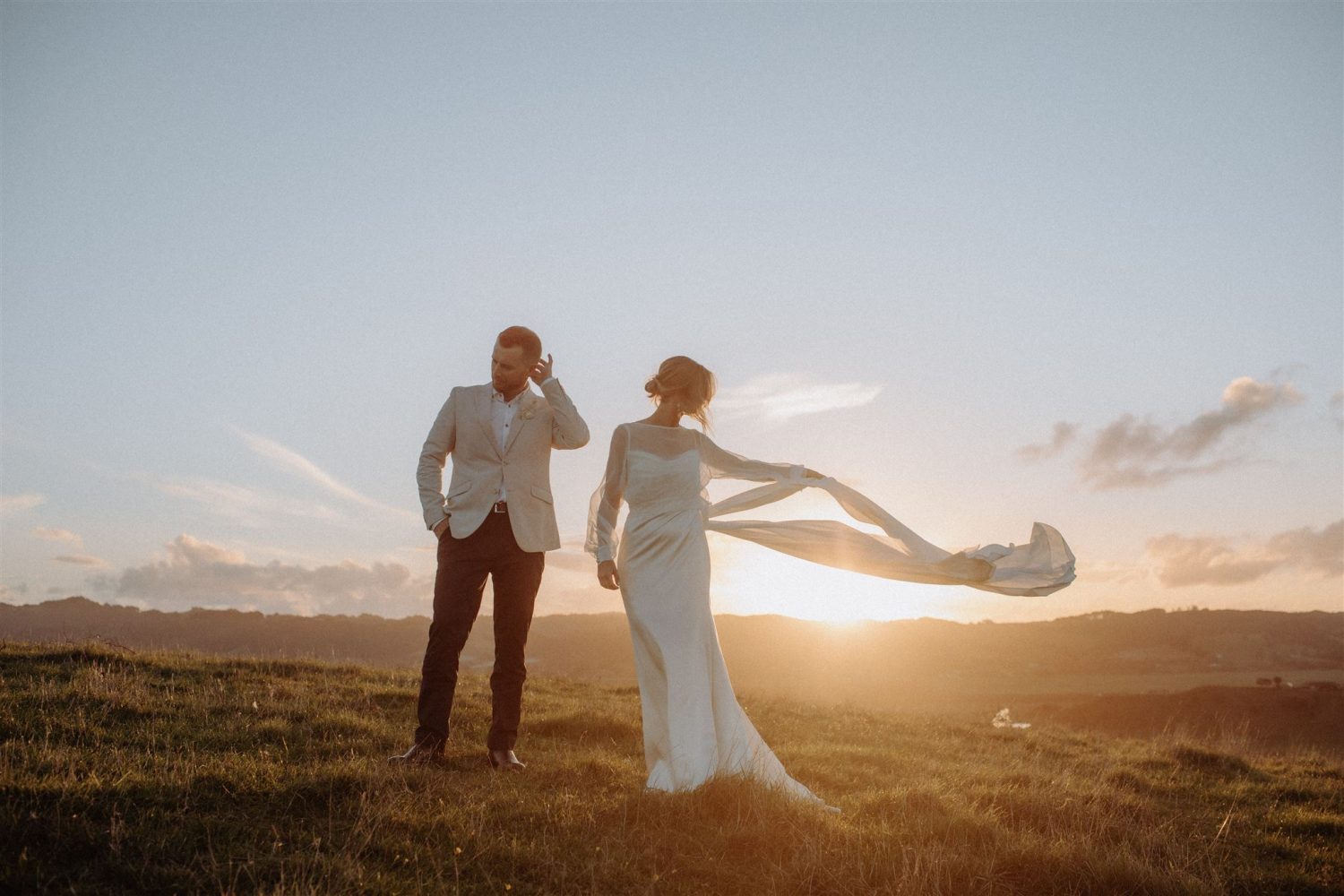 Bride and groom waiting for the sun to set feeling the fresh breeze passing them by Ana Galloway Photography