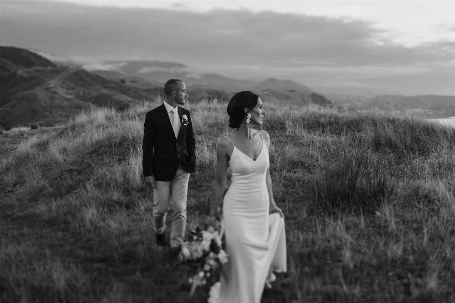 Bride and groom walking and on top of a hill looking at the beautiful view at the Summer House in Nelson. Ana Galloway Photography