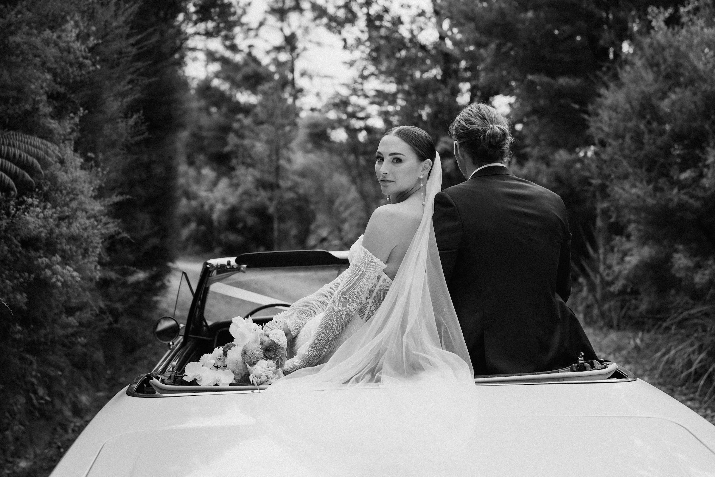 bride and groom sitting in their bridal car as the bride looking back