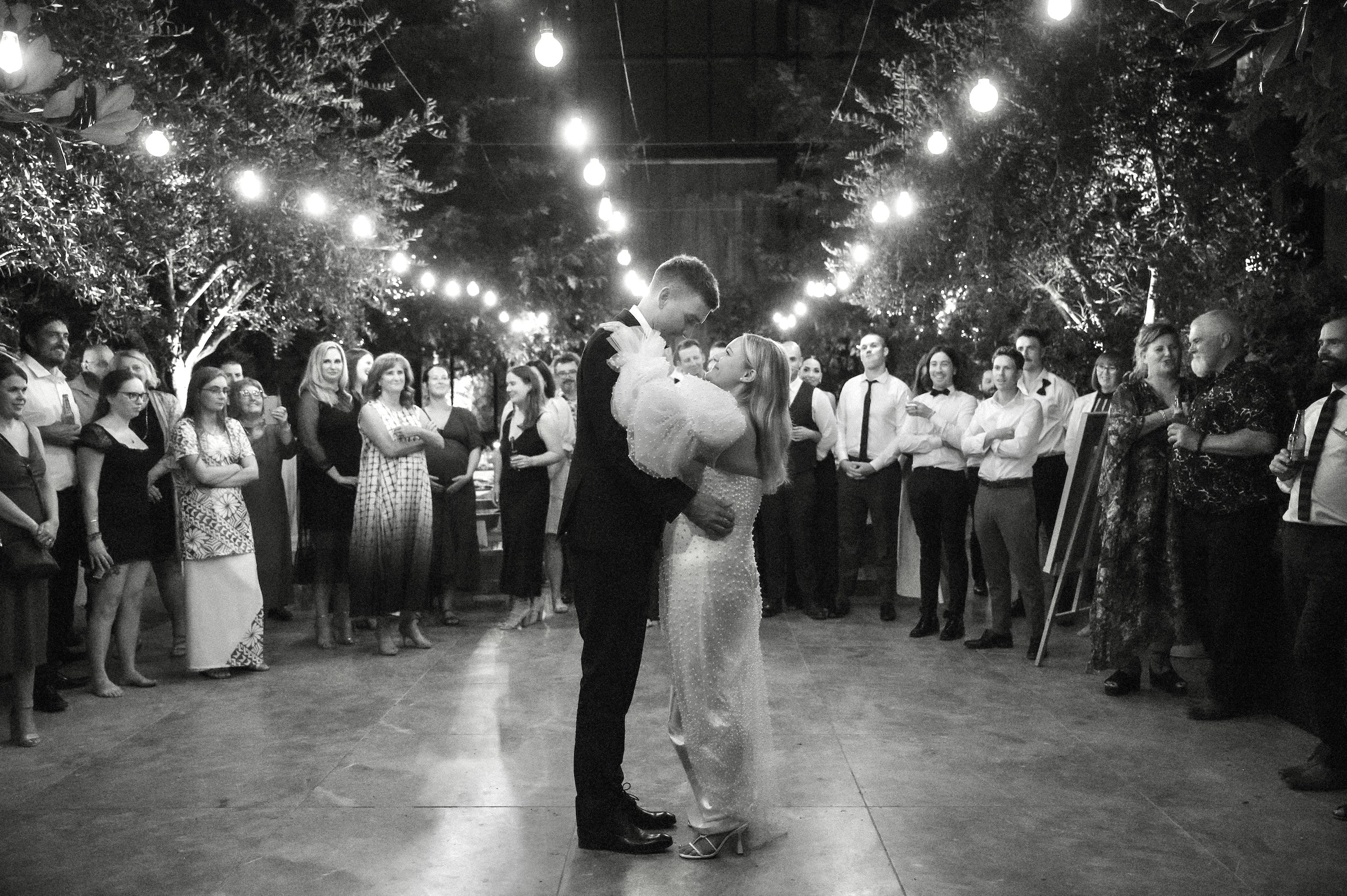 Bride in statement Cristie Nicole wedding dress covered in pearls on the dance floor with the groom dressed in a black tuxedo at The Glasshouse Morningside Auckland City Wedding Ana Galloway