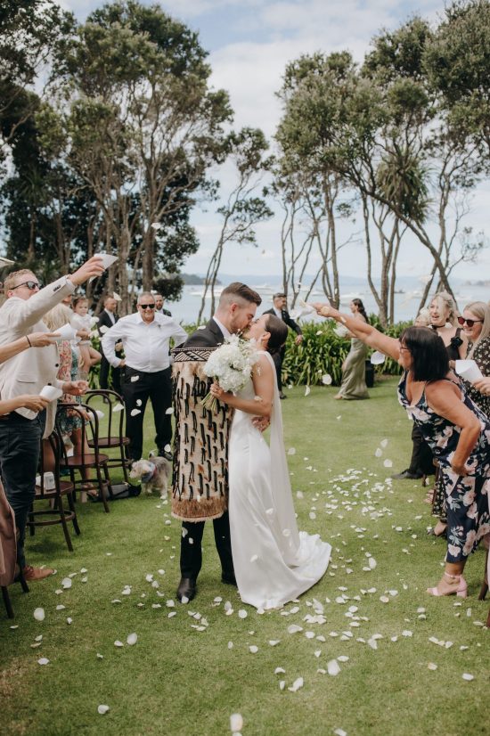 bride and groom sharing kiss as husband and wife with friends and family. Ana Galloway Photography
