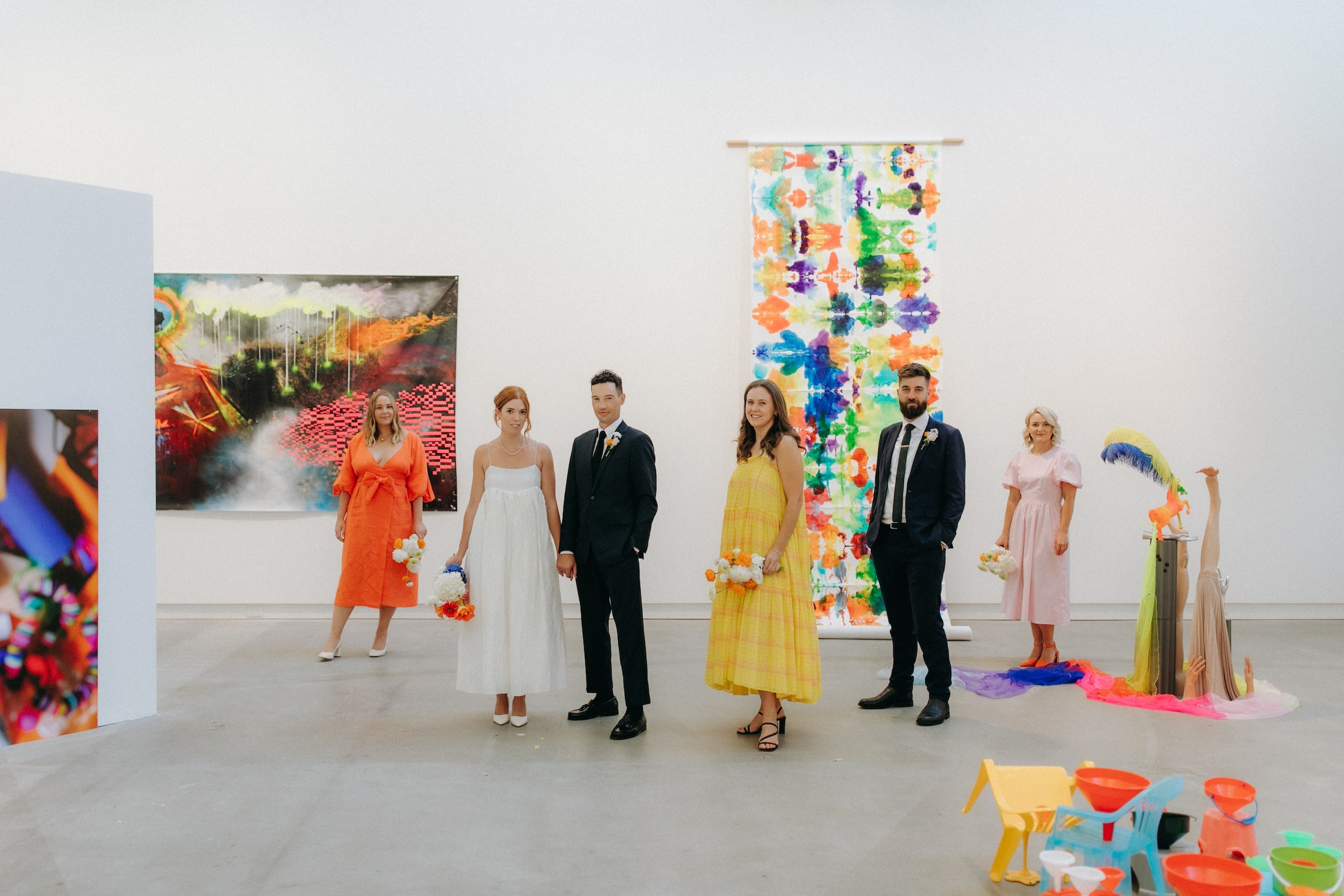 Bride and groom and colourfully dressed bridal party in art gallery Christchurch Wedding Ana Galloway Photography